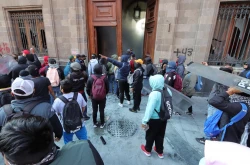 Jóvenes de Ayotzinapa derriban una puerta del Palacio Nacional con López Obrador adentro